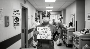 Un medico in corsia regge un cartello "E adesso non chiamateci eroi!"